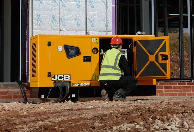Technician servicing a JCB generator on a building site